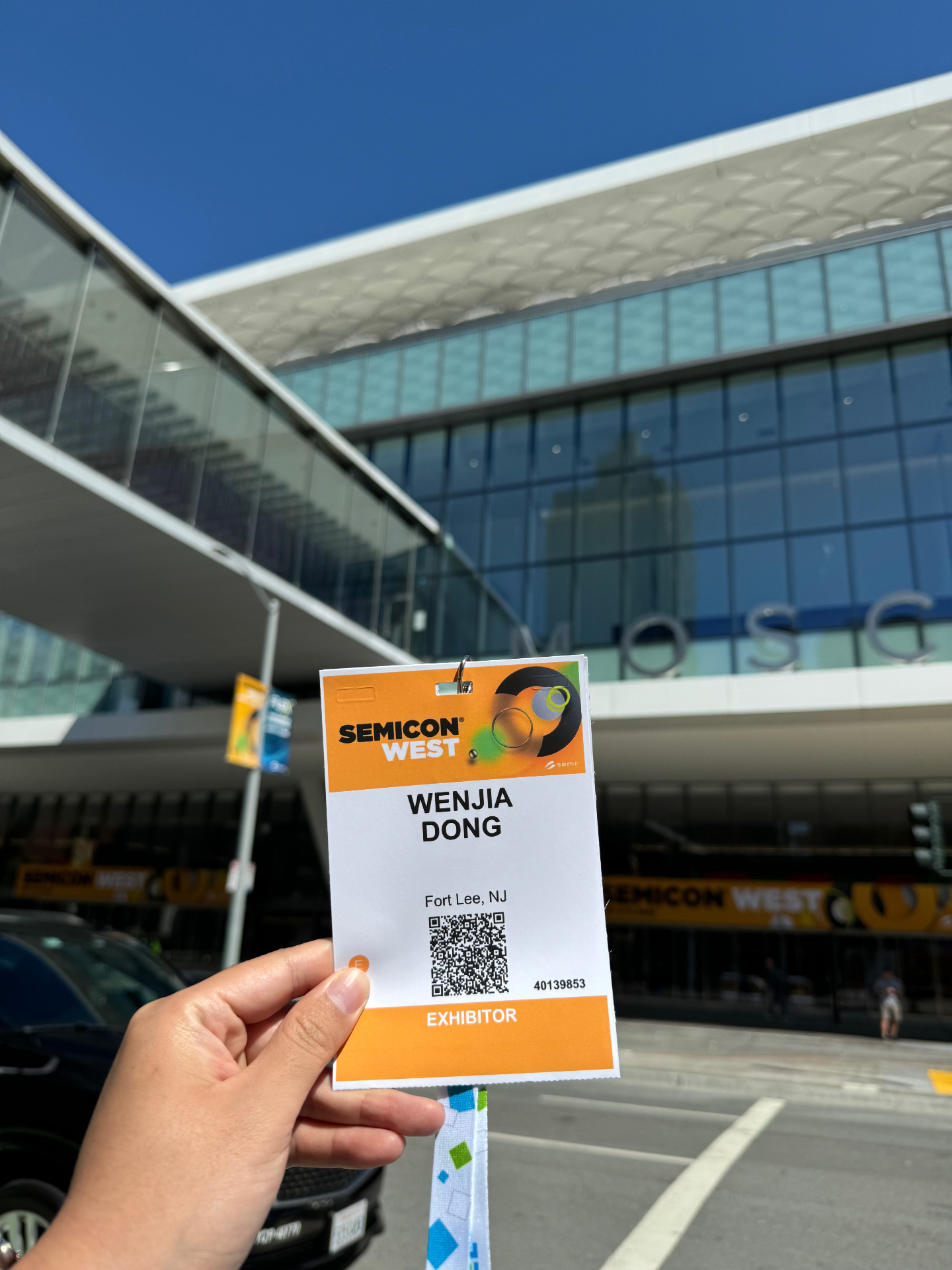 SEMICON West 2024 exhibitor badge held in front of the Moscone Center in San Francisco